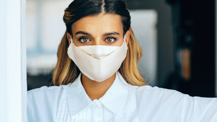 Portrait of a young woman  in white with mask covering face for covid virus protection