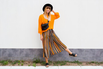 Full length image of  stylish woman  standing on white background in stylish orange sweater and...