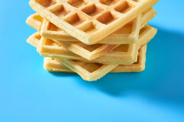 Stack of vanilla belgian waffles on blue background