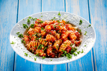 Fusilli with tomato sauce, meat and parmesan on wooden table
