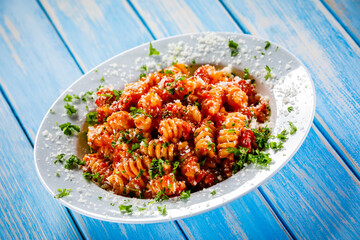Fusilli with tomato sauce, meat and parmesan on wooden table
