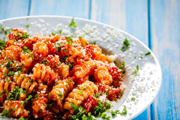 Fusilli with tomato sauce, meat and parmesan on wooden table
