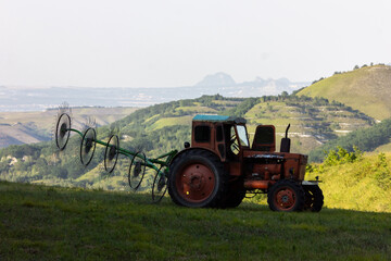 Fototapeta premium Tractor for collecting dry grass. Collection of hay.