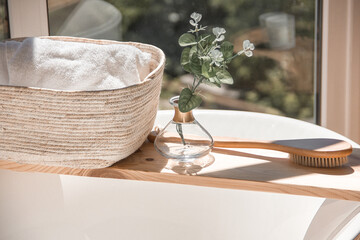 Fototapeta na wymiar bath accessories on a wooden shelf on the bath. boho style bathroom at morning in sun lights