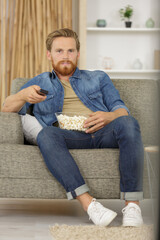 Fototapeta premium portrait an attractive man eating pop corn while watching tv