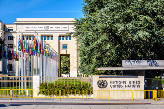 Geneva, Switzerland - September 3, 2020: Entrance of the Palace of Nations, home of the United Nations Office at Geneva (UNOG), with the avenue of flags on a sunny summer day.