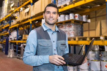 man using laptop in a warehouse