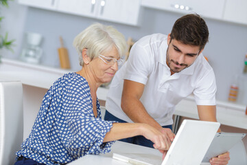 youngerman helping an elderly person using laptop computer