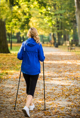 Nordic walking - middle-age woman working out in city park
