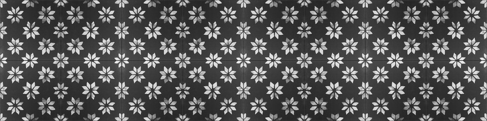 Old black anthracite white vintage worn shabby seamless square patchwork tiles stone concrete cement wall texture wide background banner panorama wallpaper, with flower print