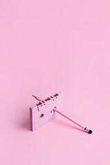 Old audio cassette and pencil on the pink table. Manual rewind of the film in the cassette....