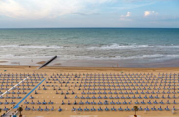 Rows of blue and white parasols and sunbeds on the beach. Italy.