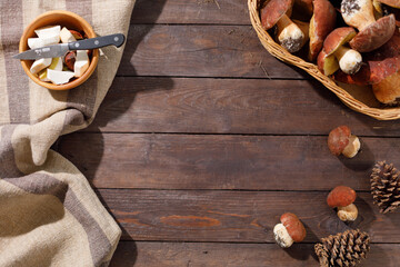 Harvest concept. Wild porcini mushrooms in a handmade wicker basket on a wooden background top view. Flat lay.