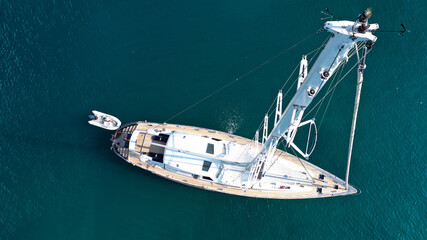 Aerial drone top down photo of beautiful sailboat anchored in Aegean sea