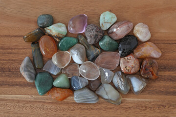 Which healing stones are you attracted to - selection of different coloured tumbled healing crystals on a brown wooden background 
