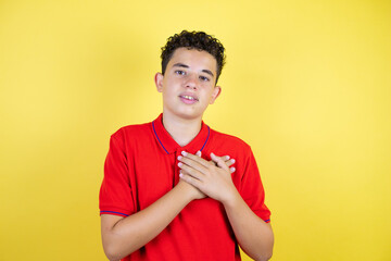 Beautiful teenager boy over isolated yellow background smiling with her hands on her chest and grateful gesture on her face.