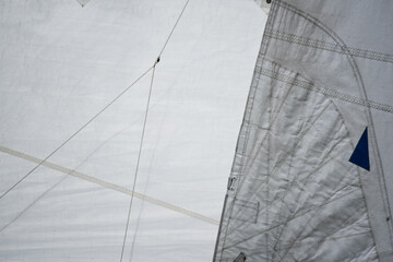 Close up of the stitching of a jib and a mainsail with lazy jacks.