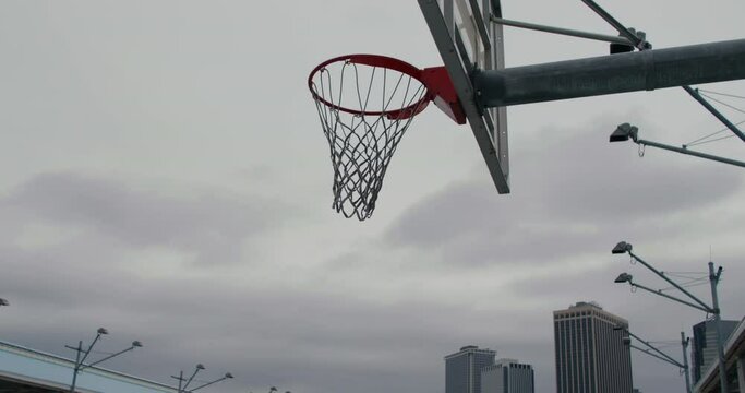 View of a basket on an empty basketball court in NYC, Manhattan business district in the background