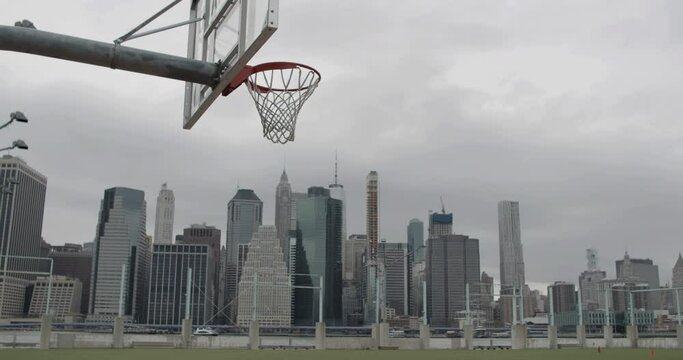 View of a basket on an empty basketball court in NYC, Manhattan business district in the background