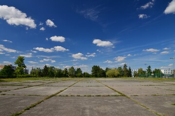 Concrete sports area. A grassy sports area of the school playground. Ready for sports. Background with blue sky and clouds.