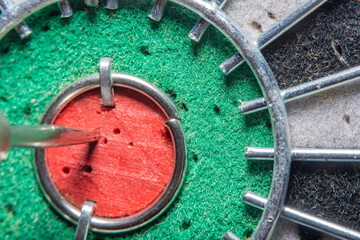 Blurred in soft focus at high magnification background with a part of an dart board with a close-up of the center (Bull's eye)with numerous holes from previous hits and an arrow stuck in the center