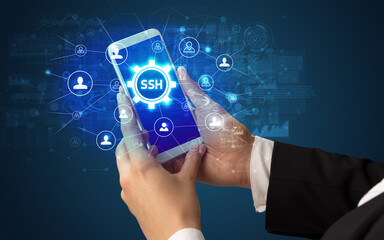 Female hand holding smartphone with SSH abbreviation, modern technology concept