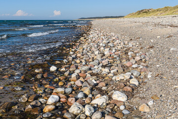 Fototapeta na wymiar Kiesel Strand mit Blauem HImmel, Dünen, Wolken und Meer, Dänemark