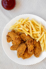Homemade Crispy Chicken Wings and French Fries with ketchup and glass of cold beer, top view. Overhead, from above, flat lay.