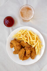 Homemade Crispy Chicken Wings and French Fries with glass of cold beer, overhead view. Top view, from above, flat lay.
