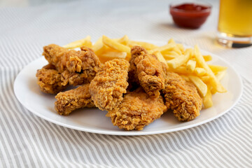 Homemade Crispy Chicken Wings and French Fries with glass of cold beer, side view. Close-up.