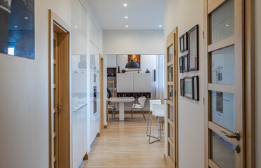 Contemporary interior of luxury apartment. Living room with table and chairs. White walls. Wooden doors.