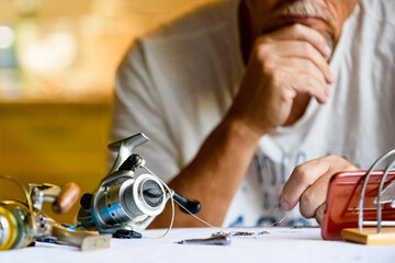 An adult man is preparing to go fishing. Watching tutorial videos on the Internet. Sharpness on reels and smartphone