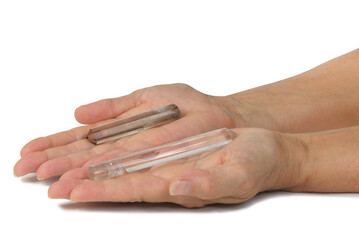 Crystal Therapy Energy in Energy Out concept - Female open palms with left clear quartz terminated crystal pointing inwards and right hand smoky quartz wand pointing outwards isolated on white 
