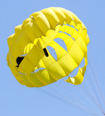 A yellow parachute flies in the  sky.