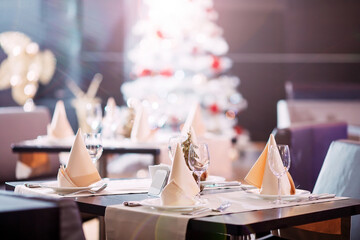 Table setting in the restaurant. Christmas tree on the background.