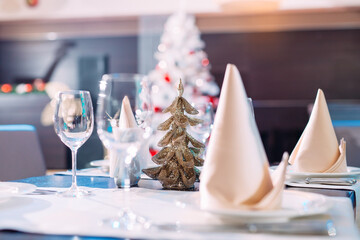 Table setting in the restaurant. Christmas tree on the background.