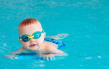 Naklejka premium Baby boy swims independently in the pool.