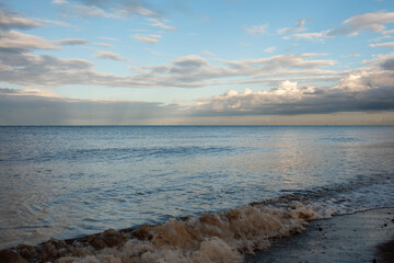Sand beach, sea and cloudy blue sky in England at sunset