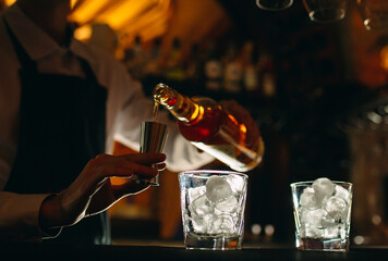 The bartender pours whiskey on the bar.