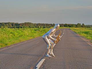 Man musician saxophonist in full body-hugging silver and silver electric suit holding golden alto...