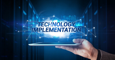 Young business person working on tablet and shows the inscription: TECHNOLOGY IMPLEMENTATION