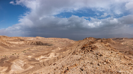 Panoramic landscape of the remote part of the Judean Desert, Israel. Hills, natural terraces with escarpments and dry wadies of the Judean Desert. Dead sea on the background.