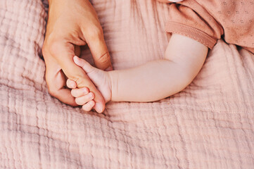 Mother and baby relaxing together, child holding mothers finger