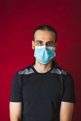 Man with mask wearing gym sportswear on red background - COVID 19