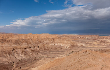 Panoramic landscape of the remote part of the Judean Desert, Israel. Hills, natural terraces with escarpments and dry wadies of the Judean Desert. Dead sea on the background.