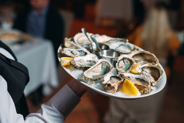 a waiter holds a serving of oysters in a restaurant.