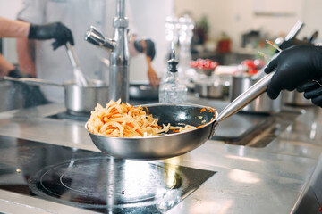 Cooks prepare meals on an electric stove in a professional kitchen in a restaurant or hotel.
