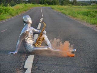 Man musician saxophonist in full body-hugging silver and silver electric suit holding golden alto...