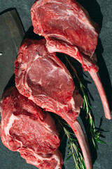 Raw steak with a meat cleaver on a dark stone background.