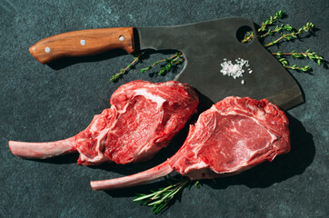 Raw steak with a meat cleaver on a dark stone background.